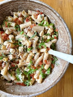 a bowl filled with pasta salad on top of a wooden table