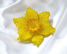 a yellow beaded flower sitting on top of a white cloth