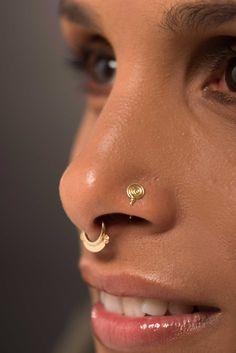 a close up of a woman with a nose ring on her nose and gold piercing