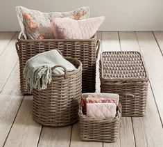 three wicker baskets with blankets and pillows in them on a wooden floor next to a window