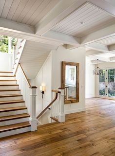 an empty room with wooden floors and white walls is pictured in this image, there are stairs leading up to the second floor