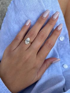 a woman's hand with a ring on it and a light blue shirt in the background