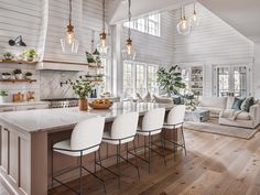 a large open concept kitchen and living room with white walls, wood floors and high ceilings