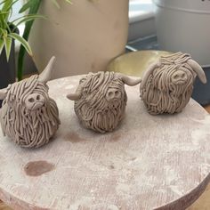 three ceramic bison heads sitting on top of a wooden table next to a potted plant