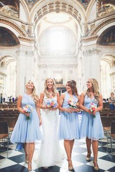 four bridesmaids in blue dresses are standing together at the alter with their bouquets