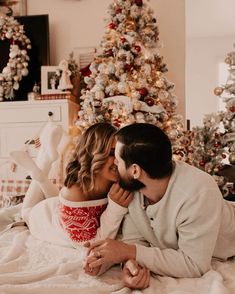 a man and woman laying in front of a christmas tree