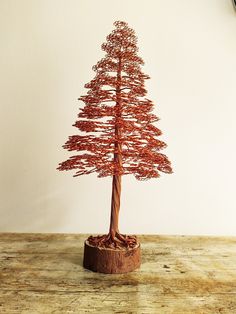 a red wire tree sitting on top of a wooden table