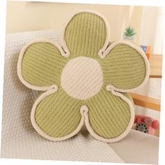 a green and white flower shaped pillow sitting on top of a bed