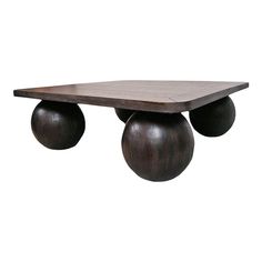 a wooden table with three black balls on it's legs and a white wall in the background