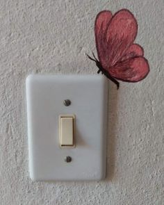 a white light switch with a red butterfly on it's back side and a pink flower attached to the wall