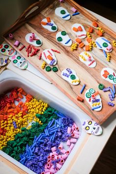 a wooden tray filled with lots of different colored beads next to a cutting board full of cut outs