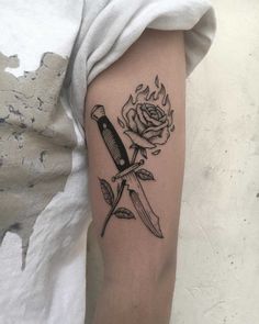 a knife and rose tattoo on the arm