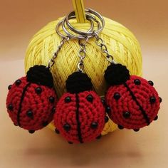 two crocheted ladybug keychains hanging from a ball of yarn