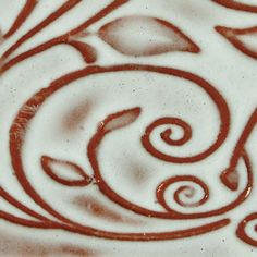 a white and red swirl design on a square tile