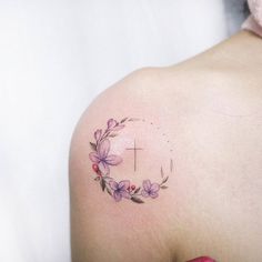 a woman's shoulder with a cross and flowers on the left side of her arm