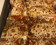 a pizza sitting on top of a metal pan covered in cheese and sauce toppings