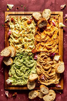 an overhead view of bread and dips on a cutting board with other food items