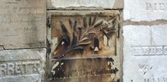 a close up of a plaque on the side of a building with flowers and leaves