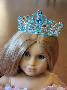 a doll with blonde hair wearing a tiara on her head and dress is looking at the camera