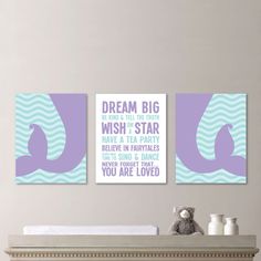 two purple and blue wall art pieces on the wall above a baby's crib