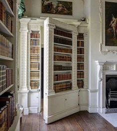 the room has many bookshelves in it, and there are paintings on the wall