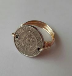 an image of a ring with a coin on the front and side, sitting on a white surface