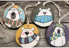 four handmade ornaments with polar bears on them are hanging from twine strings and hung on wood planks