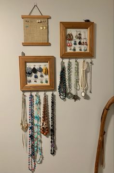 two wooden frames with jewelry hanging from them on the wall next to a chair and table