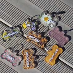 several dog bone shaped treats are on a wooden surface with flowers and beads attached to them