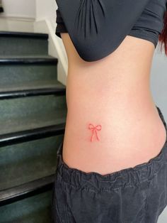 a woman with a small bow tattoo on her stomach