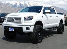 a white truck parked in a parking lot with mountains in the backgrouund