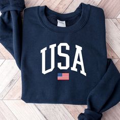 "USA Flag Sweatshirt, USA Sweatshirt, Patriotic Sweatshirt, American Flag Sweatshirt, America Sweatshirt, USA Hometown Sweatshirt ORDERING: 1. Review all photos 2. Choose Size and Color from drop-down menu 3. If personalization box is available, add your text color 4. Add each shirt to cart one at a time 5. Click \"Add to Cart\" - you can go back to add more products 6. Click \"Proceed to Checkout\" 7. Add note to seller for any requests BULK DISCOUNTS AND SPECIAL REQUESTS: We offer bulk discoun Team Spirit Fleece Tops With Graphic Print, Varsity Fleece Crew Neck Tops, Varsity Crew Neck Fleece Tops, Team Spirit Fleece Crew Top, Varsity Fleece Top With Graphic Print, Fleece Crew Top For Sports Events, Fleece Crew Neck Tops For Sports Events, Collegiate Cotton Sweatshirt With Screen Print, Fleece T-shirt With Letter Print And Crew Neck