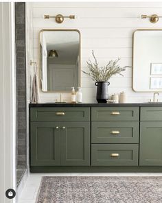 a bathroom with green cabinets and two mirrors on the wall next to a rug in front of it