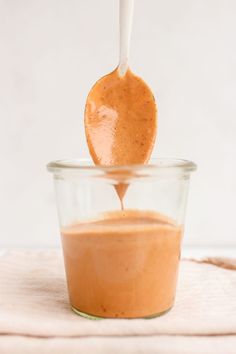 a wooden spoon is being used to dip something into a glass bowl filled with brown liquid