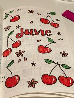 an open notebook with cherries and the word june written in red ink on it