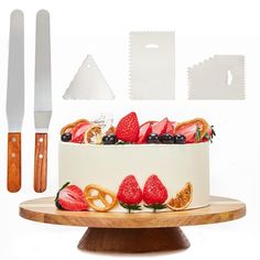 a cake decorated with fruit and pretzels on a wooden platter next to a knife