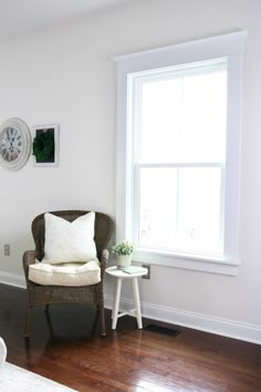 a living room with a chair, table and clock on the wall next to it