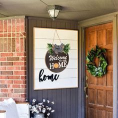 a welcome sign on the front door of a house with wreaths and potted plants