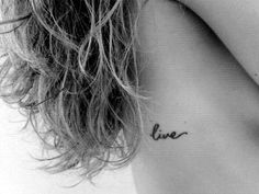 the back of a woman's neck with a small tattoo that says live on it