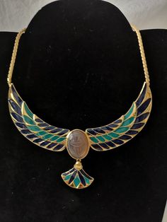 "Egyptian Winged Scarab Phoenix Egyptian Revival Cloisonne Enamel Pendant Gold necklace Ethnic Costume jewelry Luxury Evening jewelry dress Cocktail 22 carats gold plated metal, handmade cloisonne enamel, sculpted onyx cabochon. Signed jewelry by FM87 Dimensions Height 7.4\" / 19 cm Width 5.1\" / 13.2 cm Length open 13.3\" / 34.5 cm It is a vintage item, it is sold as is. Since most items have been previously used over time, they may show signs of wear. I make every effort to describe and photog Eygptain Jewelry, Egyptian Jewelry Modern, Egyptian Jewelry Necklaces, Gold Leaf Decor, Egyptian Jewellery Ancient, Egyptian Inspired Jewelry, Winged Scarab, Egyptian Inspired Jewelry Art Nouveau, Egyptian Golden Jewelry