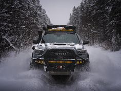 the front end of a toyota truck driving through snow