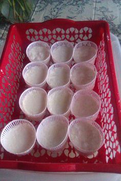 a red basket filled with lots of white cupcakes on top of a table