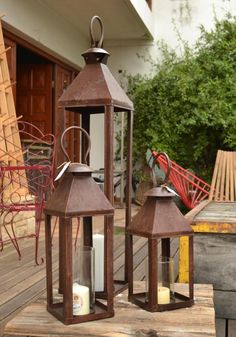 two brown lanterns sitting on top of a wooden table next to each other with candles in them