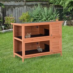 an outdoor rabbit hutch with two rabbits in it's cage on the grass