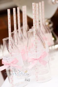 several empty wine bottles with pink bows and straws in them are lined up on a table