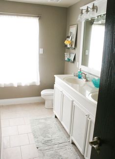 a bathroom with a toilet, sink and shower curtain in the window next to the bathtub