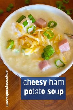 a bowl of cheesy ham potato soup with green onions and cheese on top