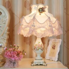 a white lamp sitting on top of a table next to a vase filled with flowers