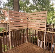 an outdoor deck with wooden slats on the top and bottom half, surrounded by trees