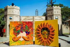 two colorful paintings on display in front of a castle